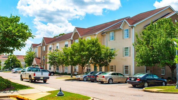 A row of townhouses with a parking lot in front. - Siegel Select Montgomery (Montgomery)