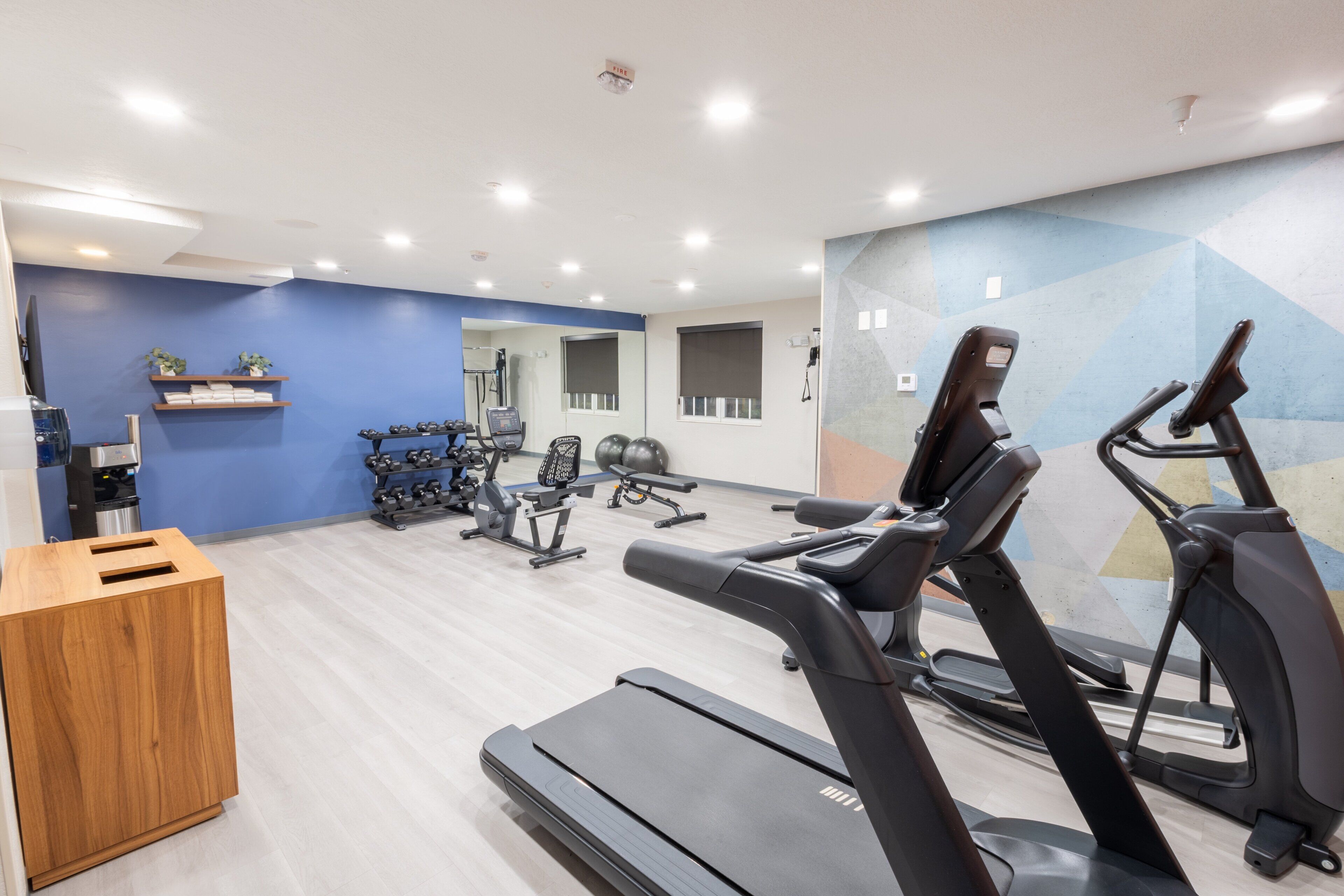A gym with treadmills, exercise bikes, and weights.