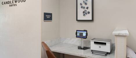 A business nook in Candlewood Suites with a marble counter, an HP printer, and a framed abstract art piece.