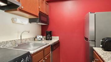 A compact kitchen with a stove, sink, microwave, coffee maker, and refrigerator.