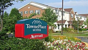 Schild für TownePlace Suites by Marriott, im Hintergrund ein Backsteinhaus.