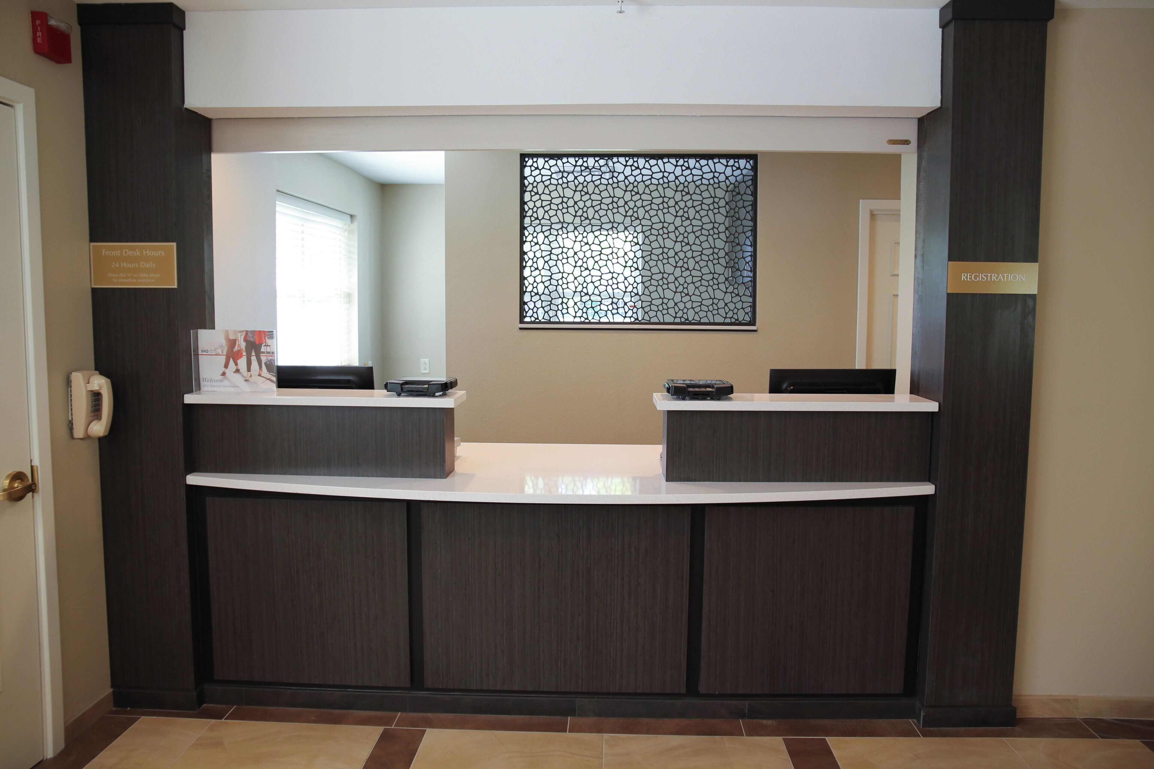 A reception desk with a sign indicating front desk hours and a registration area.