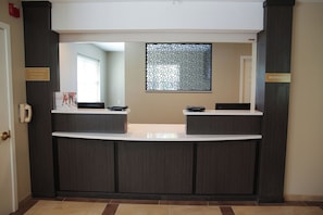 Balcão de recepção com placa indicando horário de atendimento e área de registro.