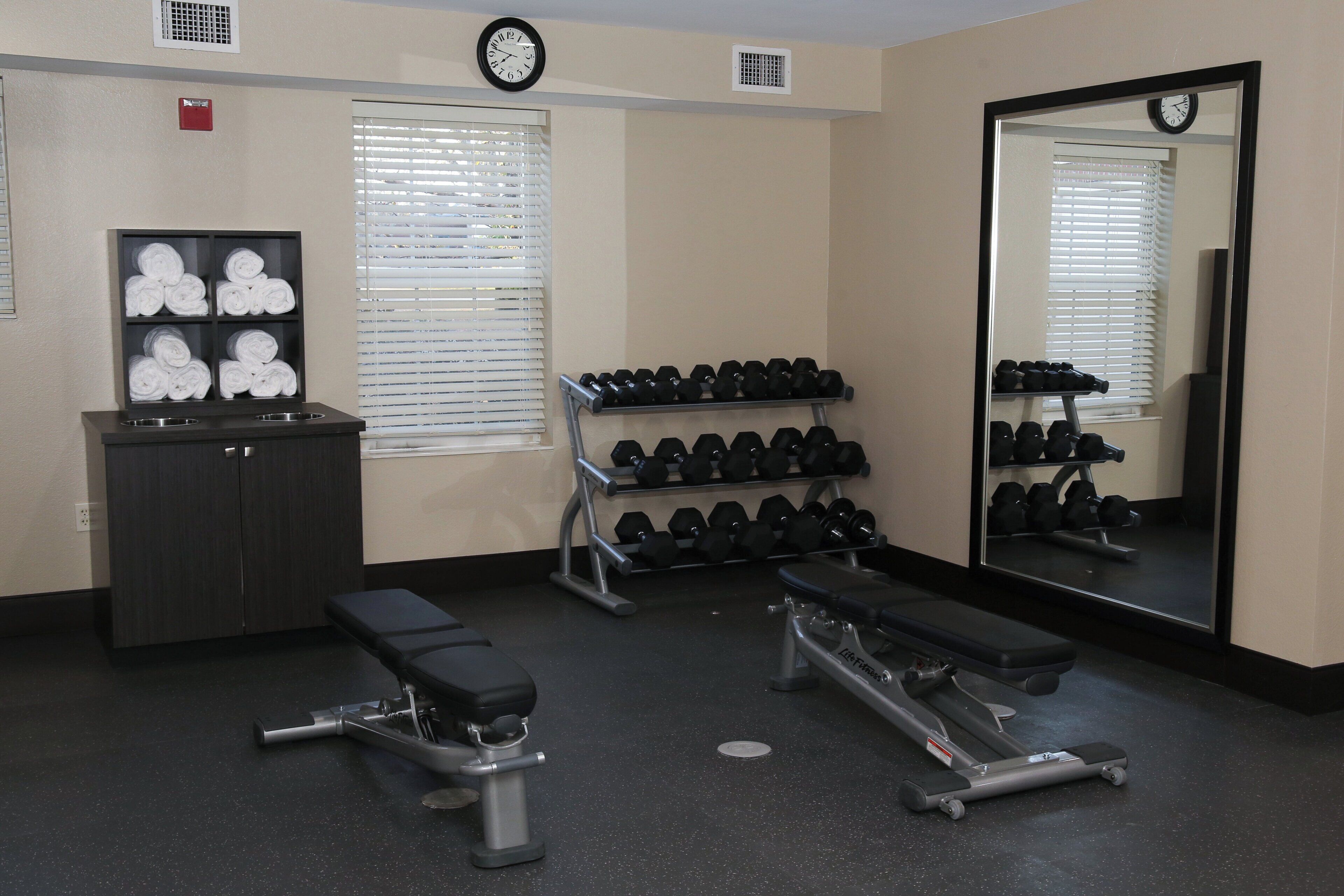 A gym with exercise equipment, a bench, and a mirror.