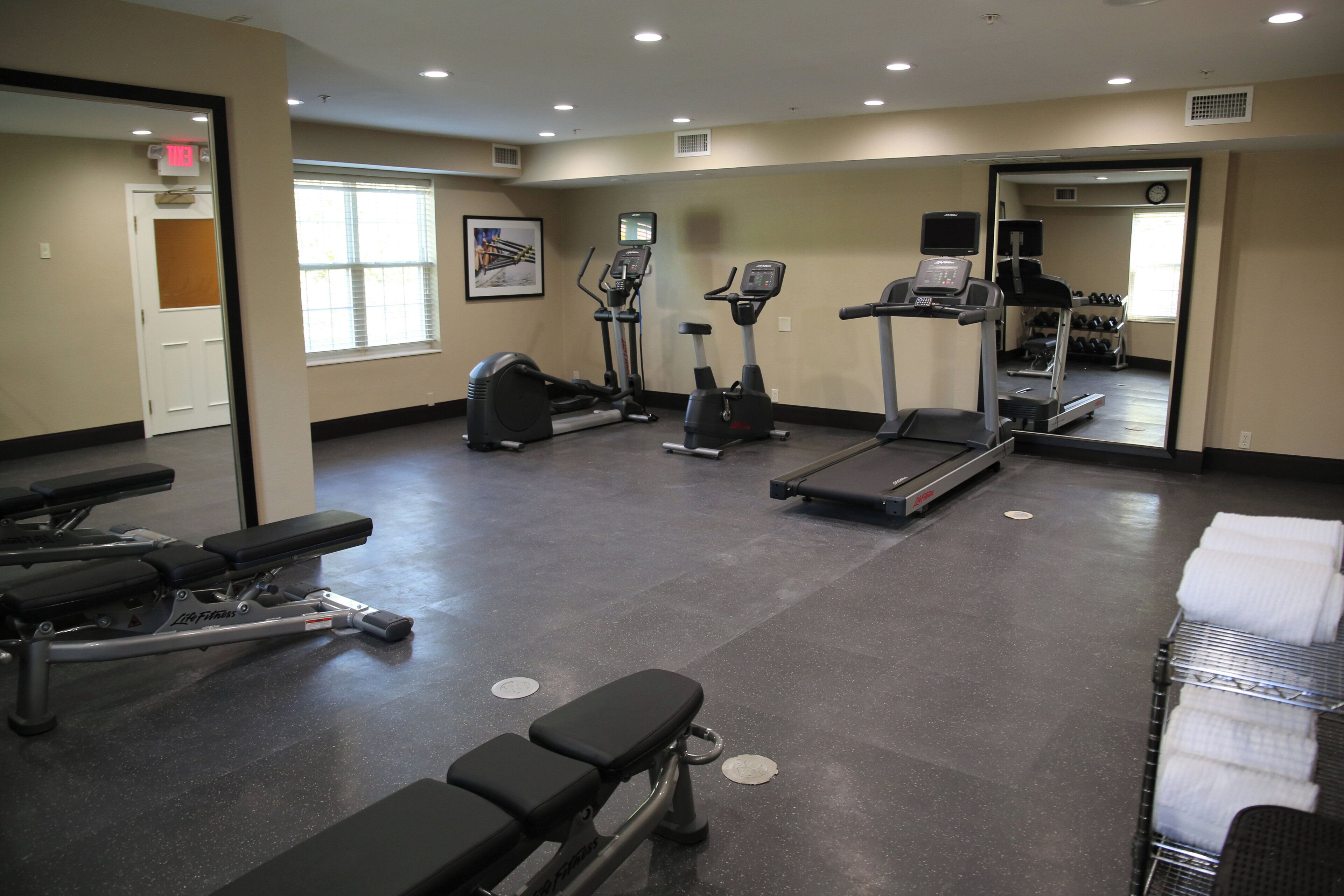 Un gimnasio con cintas de correr, elípticas y bancos de pesas.