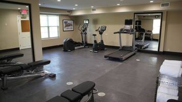 Un gimnasio con cintas de correr, elípticas y bancos de pesas.