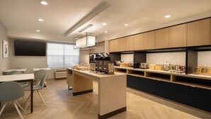 A modern kitchen with a central island, built-in appliances, and a dining area with chairs.