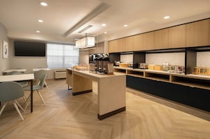 A modern kitchen with a central island, built-in appliances, and a dining area with chairs.