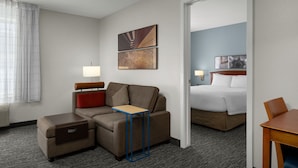 A hotel room with a sofa, a small table, a bed, and a desk.