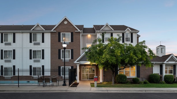 A multi-story residential building with a brick facade, a gated entrance, and a small pool area.
