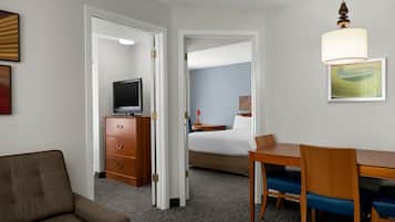 Habitación de hotel con cama, escritorio, sillas, cómoda y televisor.