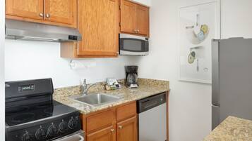A kitchen with wooden cabinets, a stainless steel stove, a microwave, a dishwasher, and a refrigerator.