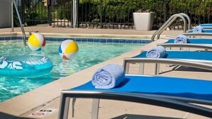 A pool area with lounge chairs, a floating pool float, and a towel rack. - Towneplace Suites By Marriott Findlay (Findlay)