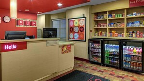 A hotel reception area with a red and beige color scheme, a reception desk, a clock, and vending machines stocked with snacks and drinks. - Towneplace Suites By Marriott Findlay (Findlay)