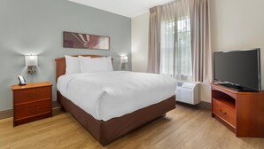 A hotel room with a large bed, a TV, a nightstand, and a window with curtains. - MainStay Suites Tampa Moffitt-USF (Tampa)