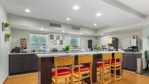 A modern kitchen with a central island, bar stools, and a coffee machine. - MainStay Suites Tampa Moffitt-USF (Tampa)
