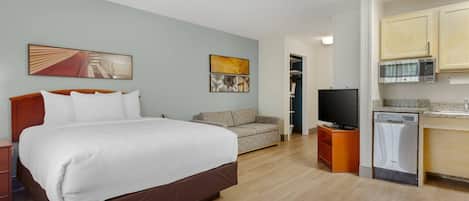 Une chambre d’hôtel avec un grand lit, un canapé, une télévision et un coin cuisine équipé d’un four à micro-ondes et d’un lave-vaisselle.