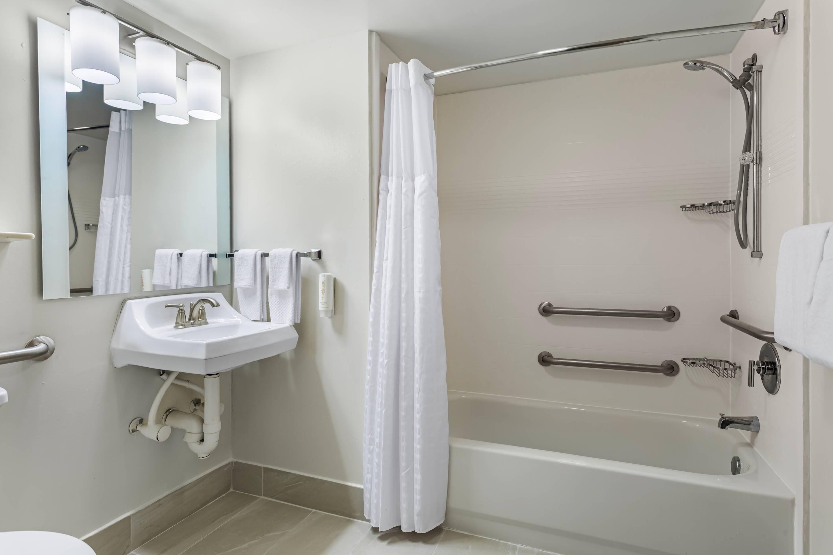 Een moderne badkamer met een witte wastafel, spiegel en bad.