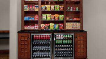Een automaat voor snacks en drankjes met meerdere planken vol lekkernijen en twee drankdispensers.
