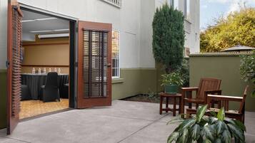 An open door leading to a room with a table and chairs, a potted plant, and a wooden bench outside.