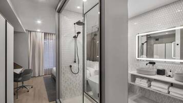 A modern bathroom with a glass-enclosed shower, a large mirror, and a vanity with a sink and towel rack.