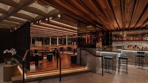 Eine moderne Bar mit Holzbalkendecke, Barhocker und einer gut sortierten Spirituosenregal.