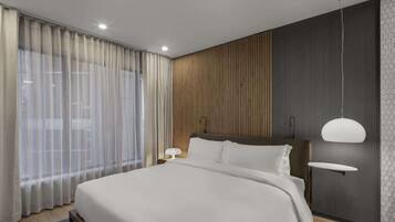 A modern bedroom with a large bed, a wooden accent wall, and a pendant light.