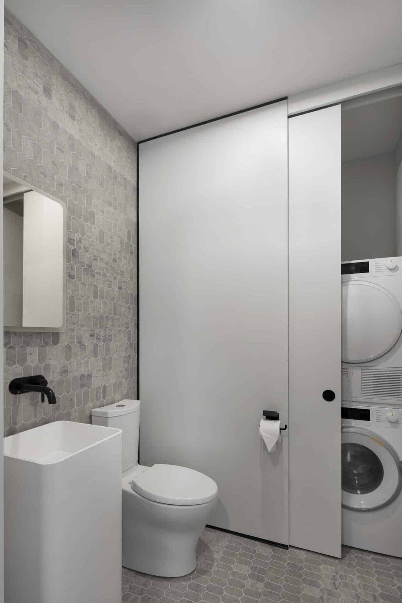A modern bathroom with a toilet, sink, and washing machine.
