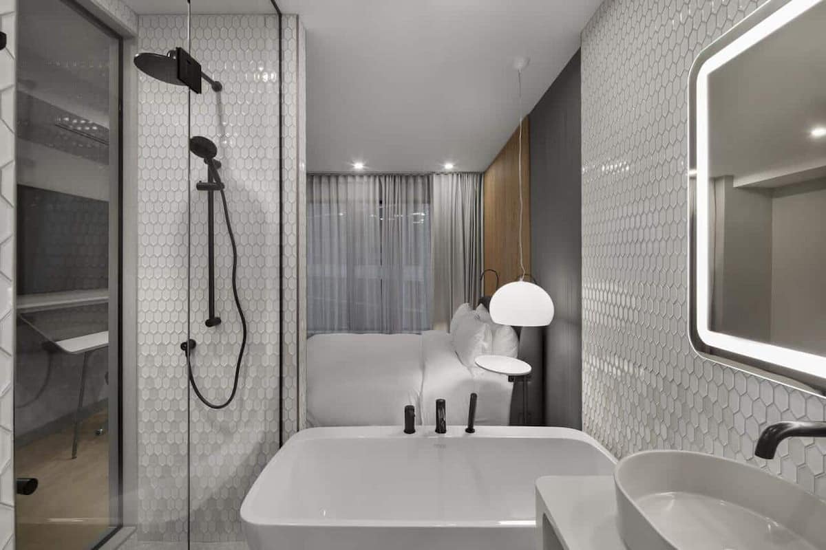 A modern bathroom with a glass-enclosed shower, a large bathtub, and a vanity with a mirror.