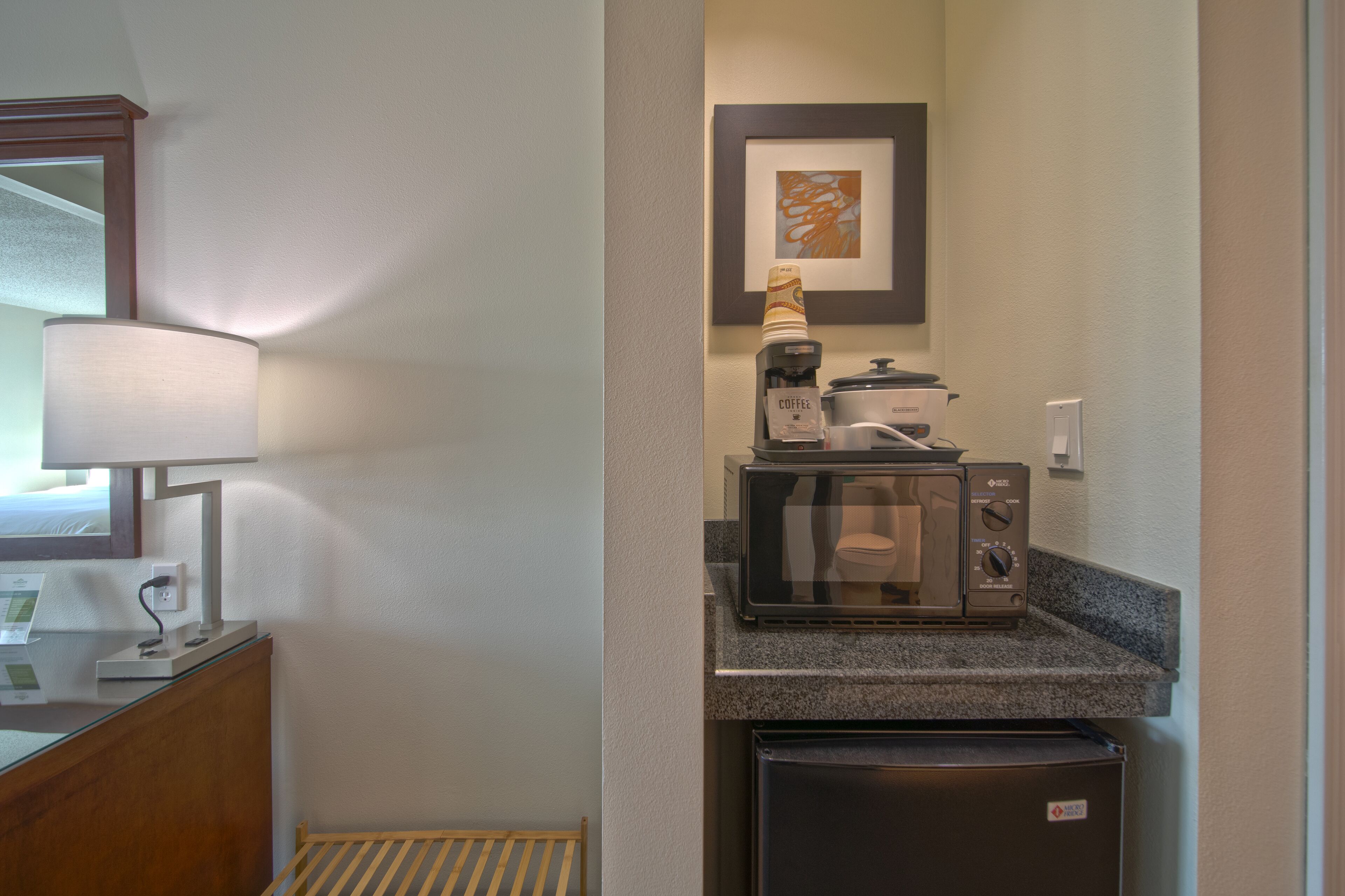 A compact kitchenette with a microwave, coffee maker, and refrigerator.