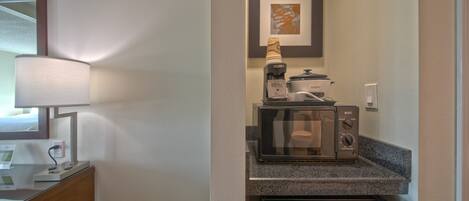 A compact kitchenette with a microwave, coffee maker, and refrigerator.