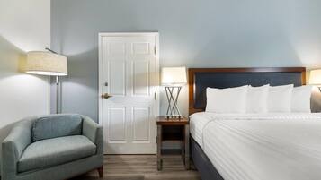 A hotel room with a bed, a nightstand, a lamp, and a chair.
