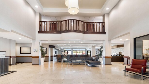 A spacious lobby with a high ceiling, a central seating area, and a reception desk. - Wingate by Wyndham - Round Rock (Round Rock)