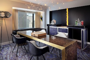 A modern hotel room with a dining area, a sofa, and a bar counter.