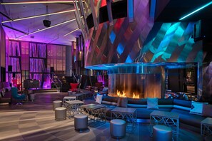 A modern lounge area with a central fire feature, seating arrangements, and a geometric wall design. - W Seattle (Seattle)