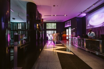 A modern hotel room with a large window, a sofa, a desk, and a TV. at W Seattle