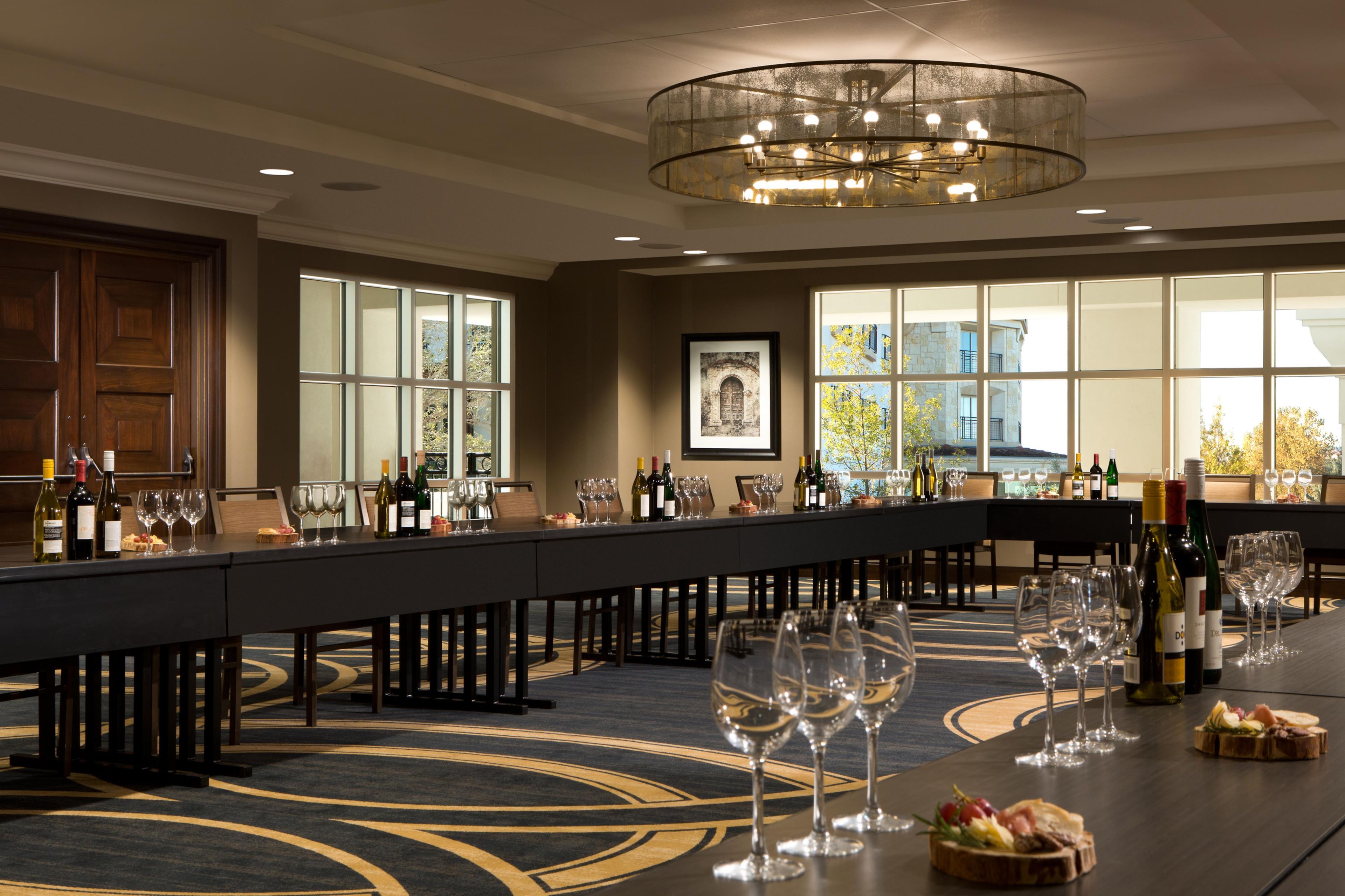A conference room with a long table set for a meeting, equipped with chairs and wine glasses.