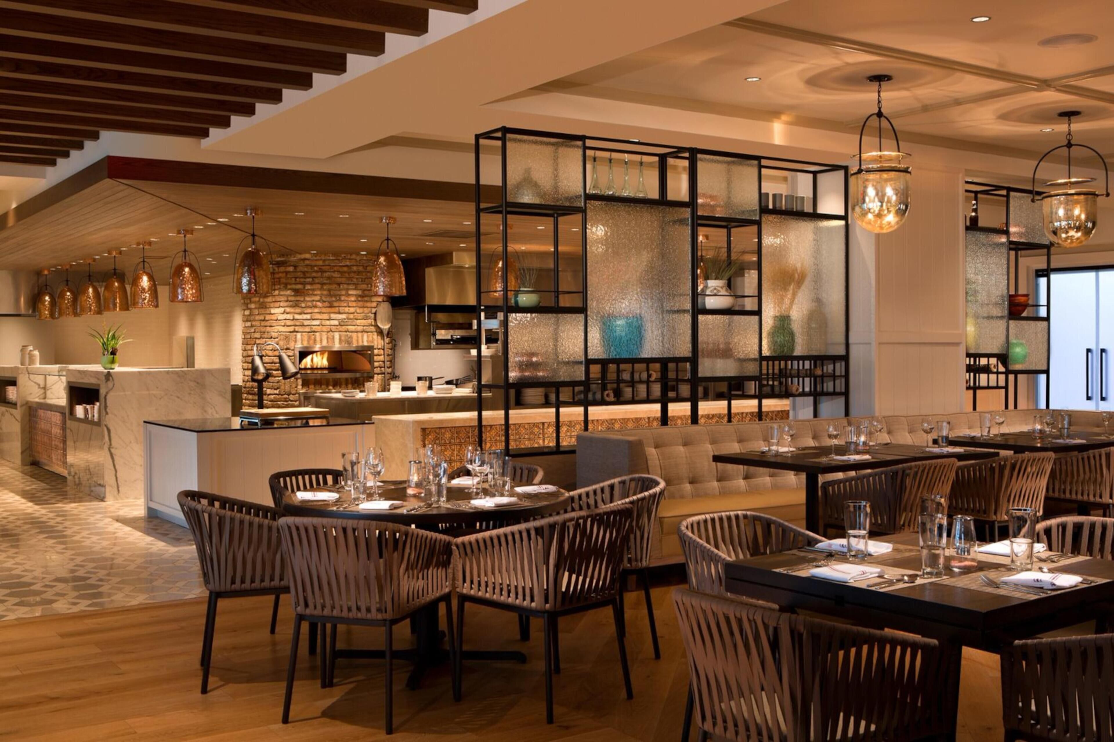A modern restaurant with a bar area, wooden flooring, and a brick wall.