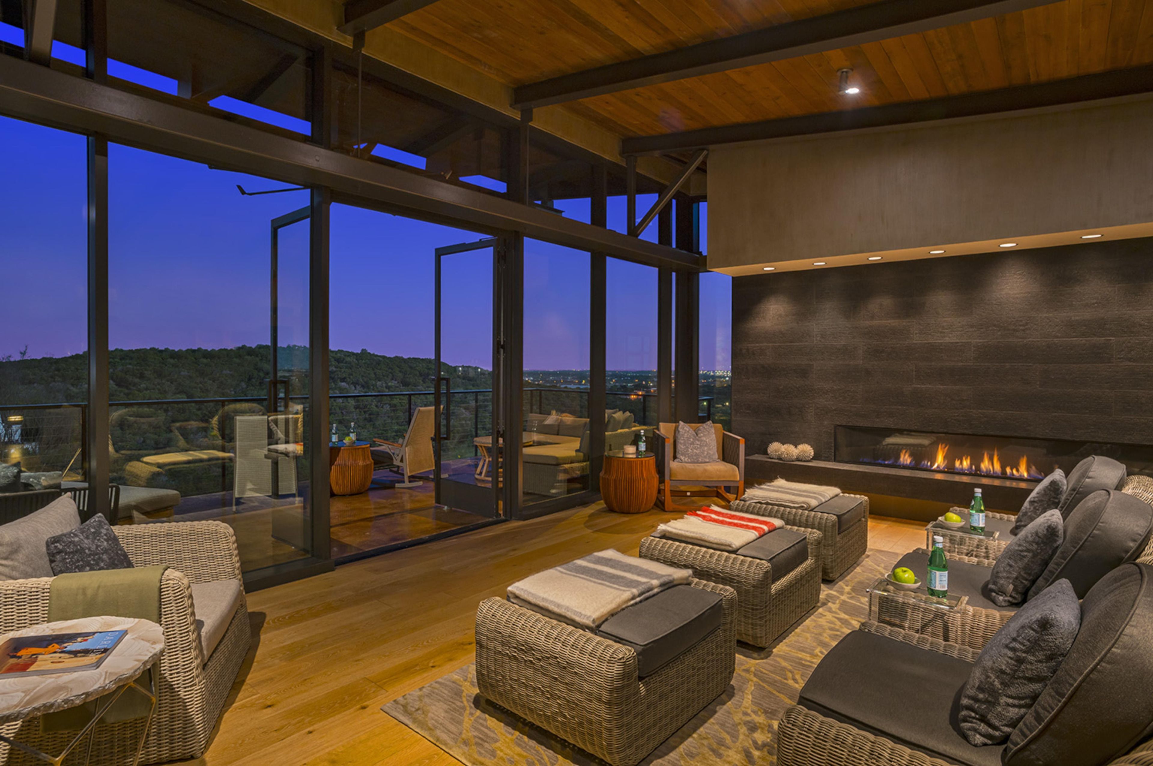 A modern interior with a fireplace, wicker furniture, and a panoramic view.