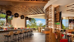 A bar area with a long counter, multiple stools, and a view of the outdoors. - Signia by Hilton La Cantera Resort & Spa (San Antonio)