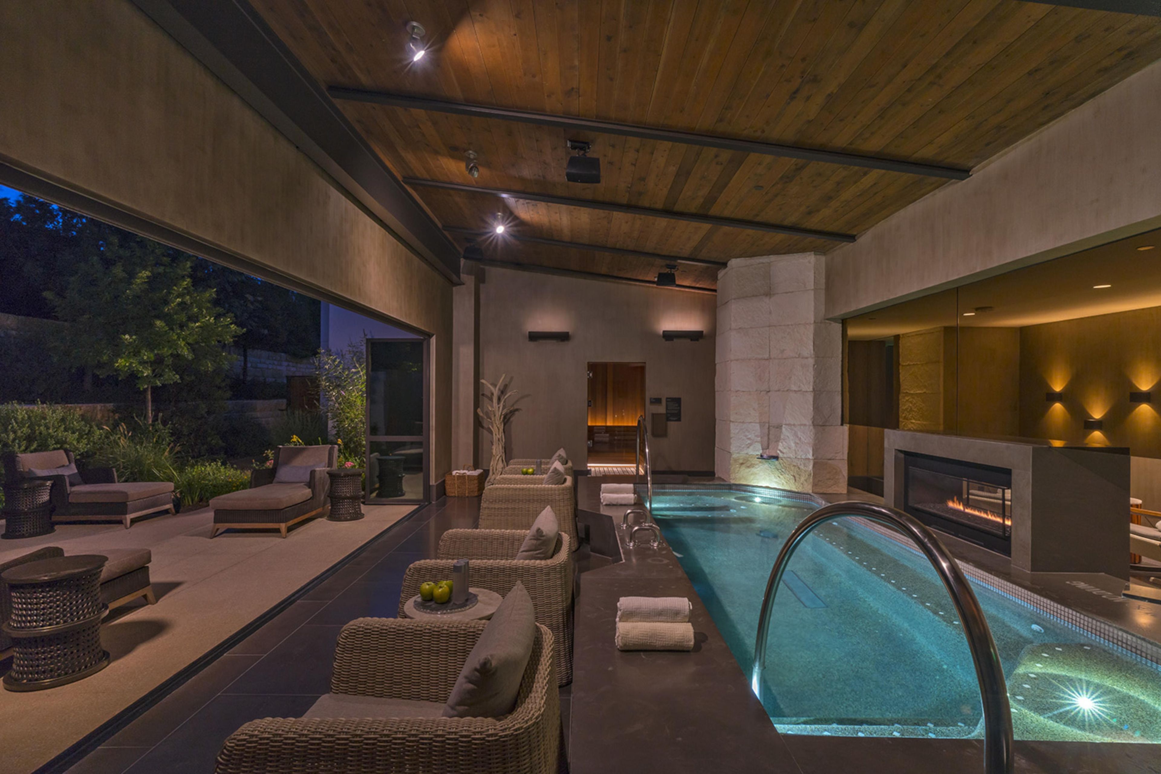 Un área de piscina interior con sillones de descanso y una chimenea.