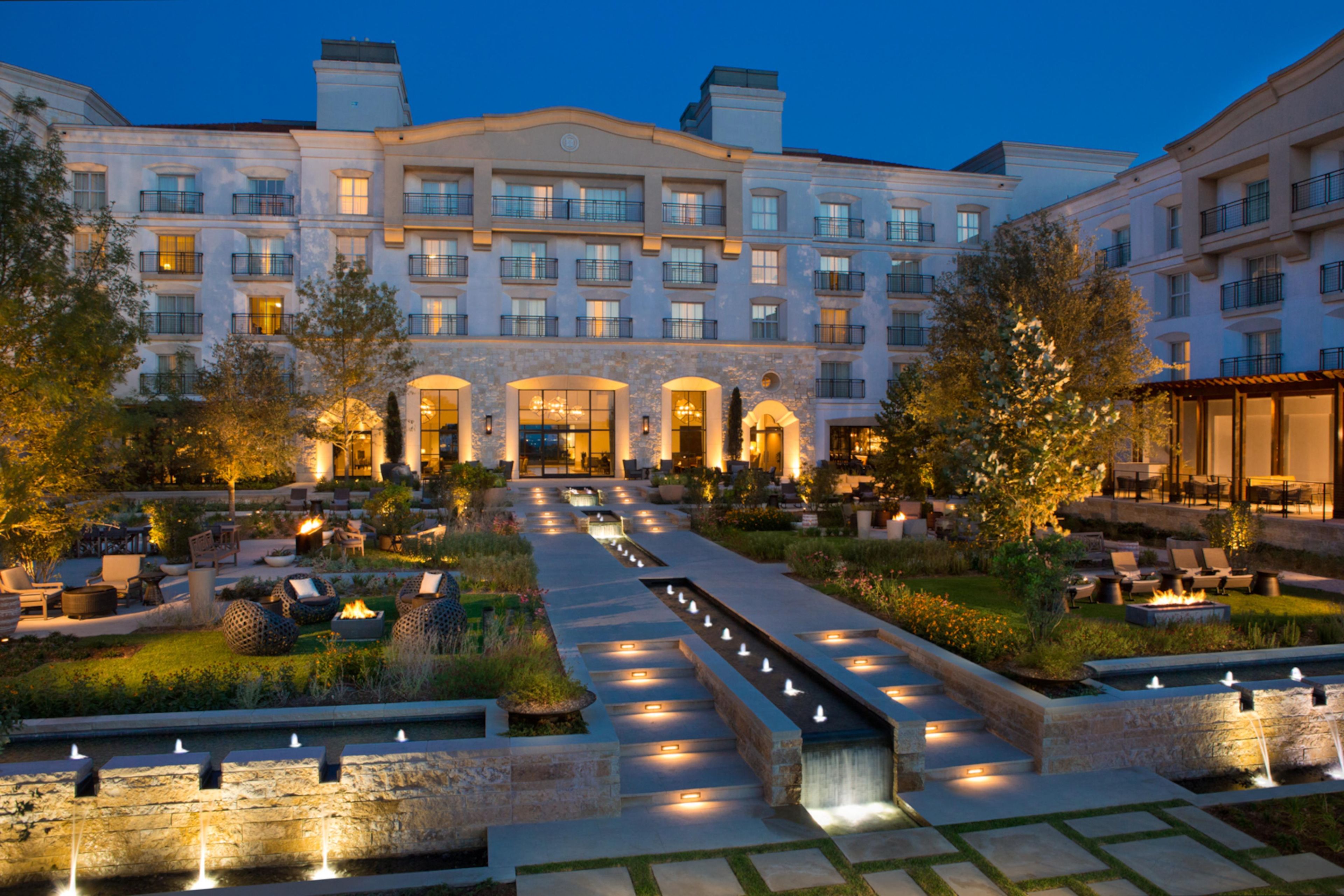 A hotel with a central courtyard, outdoor seating, and a fountain.