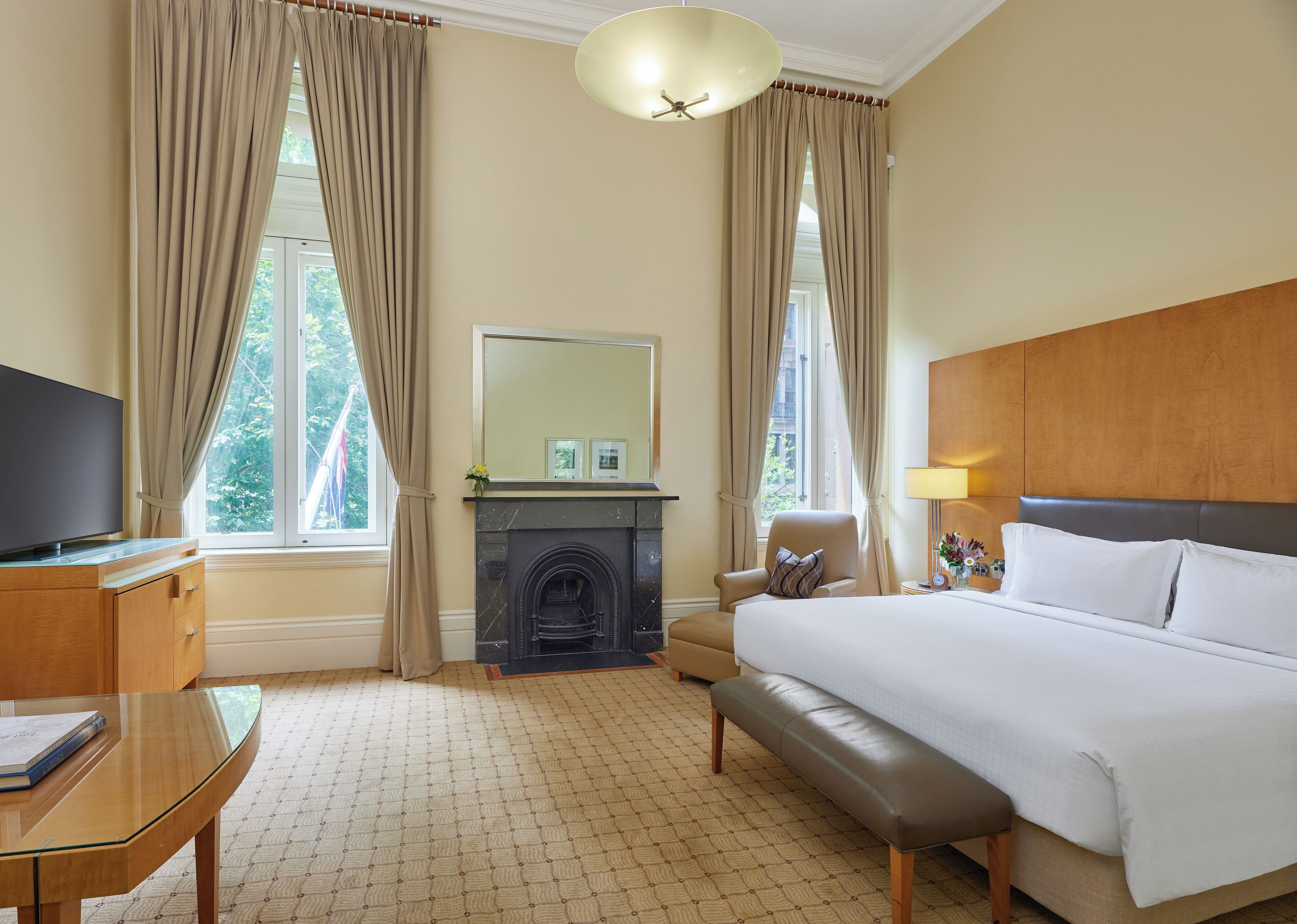 A hotel room with a bed, a television, a fireplace, and a desk.