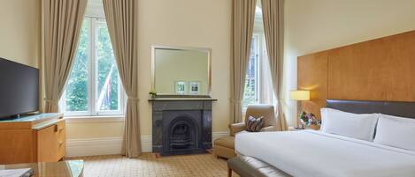 A hotel room with a bed, a television, a fireplace, and a desk.