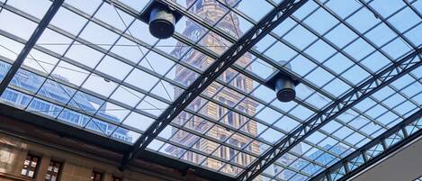 A glass-roofed atrium with a view of a historic building and a clock tower.