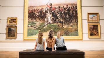 A group of people observing a large painting in a gallery.