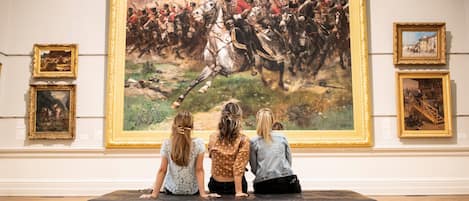 A group of people observing a large painting in a gallery.