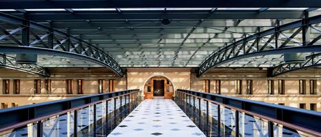 A covered pedestrian bridge with glass railings and a patterned floor.