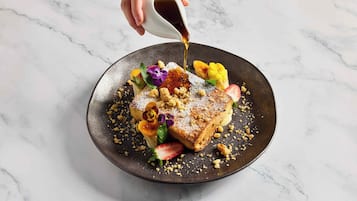 Un plato de postre con una tostada, fruta y azúcar glas.