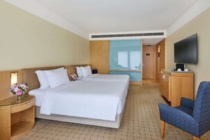 Ein Hotelzimmer mit einem großen Bett, einem Schreibtisch mit Lampe, einem Fernseher und einem Sessel.